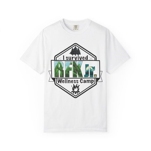 Graphic tee that says "I survived rfk jr wellness camp". The text is contained in a hexagon with a ribbon going across the middle where "rfk jr." is displayed with cartoon mountain scenery displayed in the text. at the top of the hexagon are trees and at the bottom is a campfire. Front view, color white.